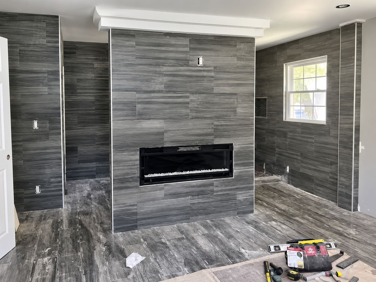 Dark gray wood-grain porcelain covering the floor, walls, and a fireplace chase of one room